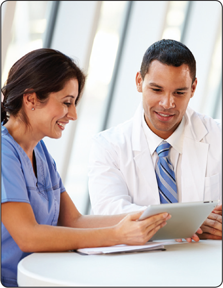 Two Healthcare professionals, sitting at a table discussing data displayed on tablet